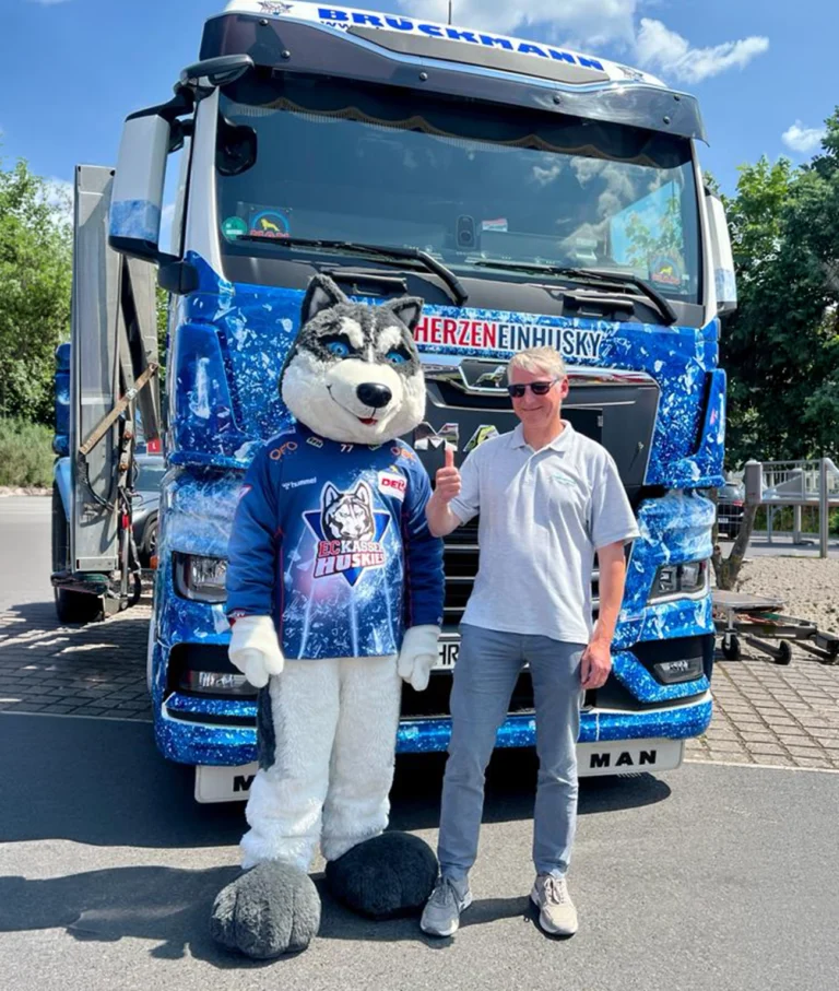 Ralf Brückmann neben einem Lkw mit dem Maskottchen der Kassel Huskies