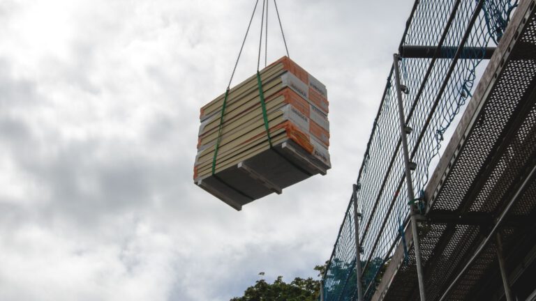 Kran hebt Baumaterial zum Gerüst auf eine Baustelle