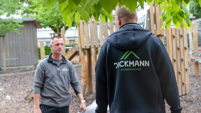 Zwei Dachdecker von Dickmann Bedachungen in Arbeitskleidung auf einer Baustelle